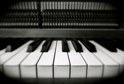 Närbild av pianotangenter i svartvitt, med pianots mekanik synlig ovanför tangenterna.