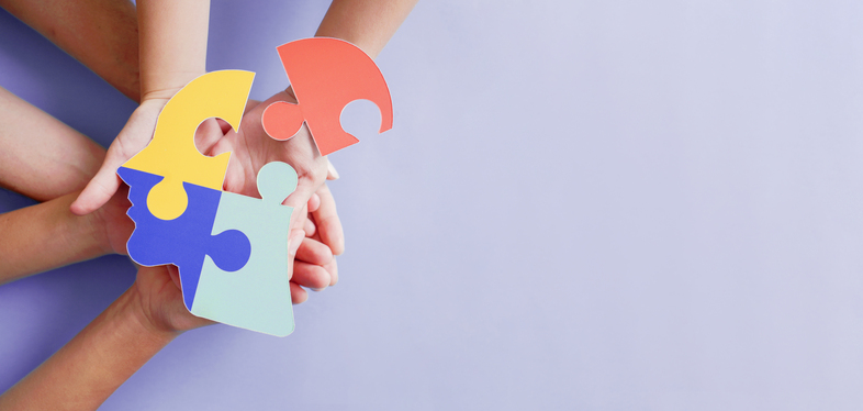 Flera händer håller färgglada pusselbitar mot en ljuslila bakgrund.