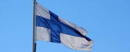 Finlands flagga vajar mot en klarblå himmel.