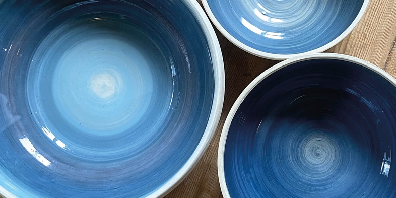 Tre blå keramikskålar på ett trägolv med texten 'Prova på: Keramik' i hörnet.