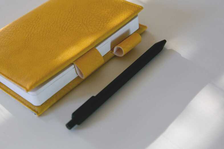 En gul anteckningsbok med en svart penna bredvid.