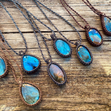 Handgjorda halsband med blå och bruna labradoritstenar på träbord.