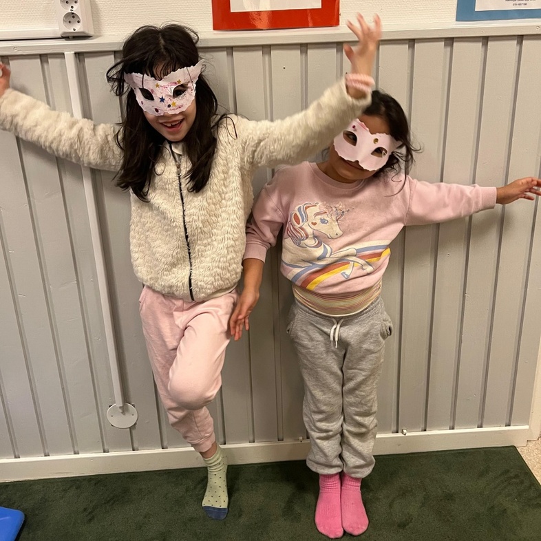 Två barn står mot en vägg, ett barn har enhörningströja och båda har färgglada strumpor.