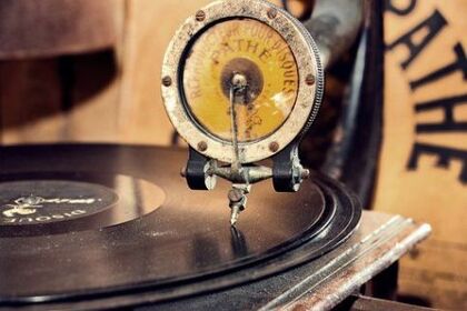 Närbild av en gammal grammofon med en stenkaka och en nålarm i fokus.