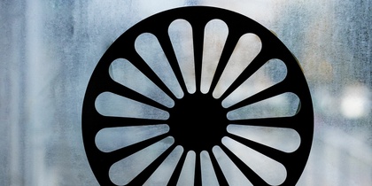 Svart hjulformad symbol med 16 ekrar på en frostad glasruta.