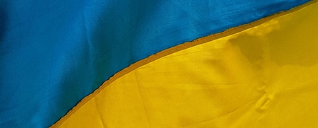 Ukrainas flagga vajar mot en blå himmel med några moln.