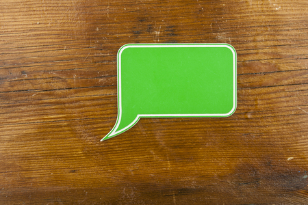 Grön pratbubbla på ett trä bord.