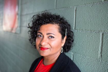 Person med lockigt hår står mot en grön tegelvägg, ansiktet är suddat för anonymitet.