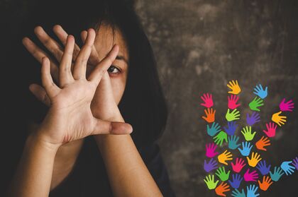 En person skyddar sitt ansikte med händerna, färgglada handavtryck syns i hörnet.