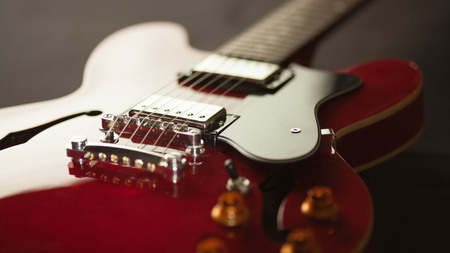 Närbild av en röd elgitarr med svarta och silverfärgade detaljer.