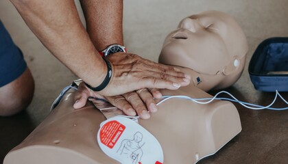 Person utför hjärt-lungräddning på en docka med defibrillatorpads under en övning.