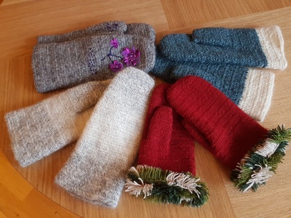 Fyra par stickade vantar i olika färger ligger på ett trägolv.