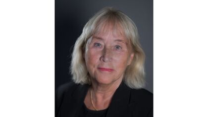 Porträtt av person med blont hår, ansiktet är suddat och oidentifierbart, mörk bakgrund.