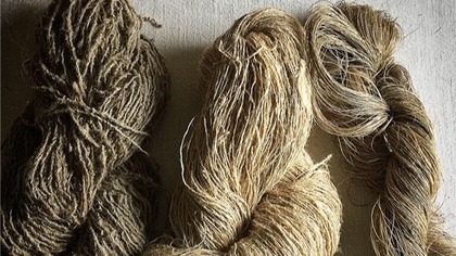 Tre buntar med grovt, naturligt garn i olika nyanser av beige och brunt ligger på ett ljust tygunderlag.