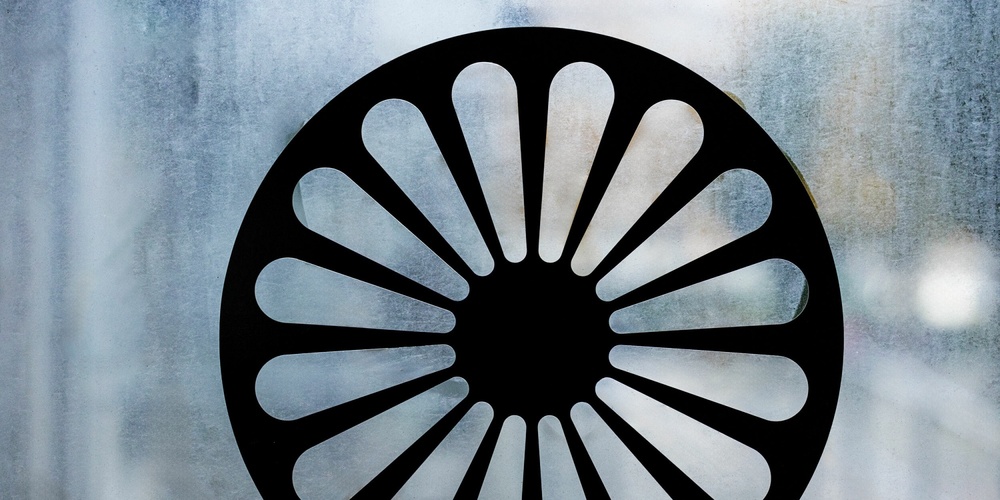 Svart hjulformad symbol med 16 ekrar på en frostad glasruta.