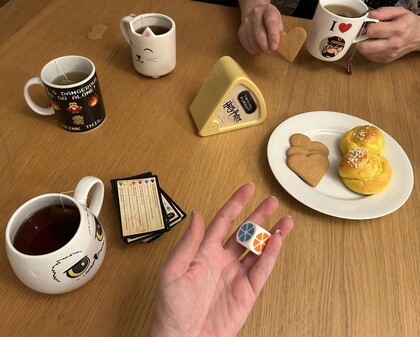 Ett bord med tre tekoppar, Harry Potter Trivial Pursuit, spelkort, tärning, pepparkakor och saffransbullar.