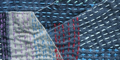 Närbild av jeanslappar med färgglada broderade stygn i olika mönster och färger.