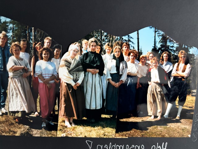 En grupp människor utomhus, många klädda i traditionella kläder, står tillsammans i en skogsmiljö.