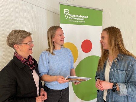 Tre kvinnor samtalar framför en rollup med texten 'Studieförbundet Vuxenskolan'.