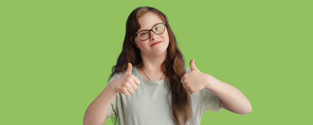 Leende person ger tummen upp med båda händerna mot en grön bakgrund.