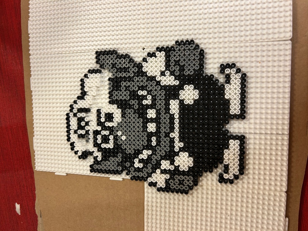 Pärlplatta föreställande en svartvit figur med stora öron och hatt på vit bakgrund.