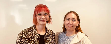 Två personer står bredvid varandra framför en vit tavla, ansiktena är suddade för anonymitet.