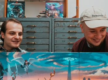 Två personer sitter vid ett bord med Dungeons & Dragons böcker, tärningar och spelledarskärm.