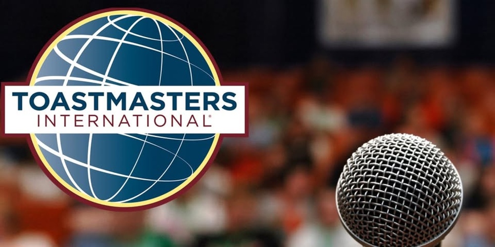 Toastmasters International-logotyp och en mikrofon framför en suddig publik.