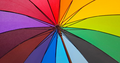 Närbild av en färgglad regnbågsfärgad paraply med vattendroppar på tyget.