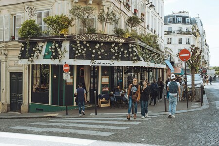 Gatubild av ett parisiskt café med människor som promenerar förbi på trottoaren.