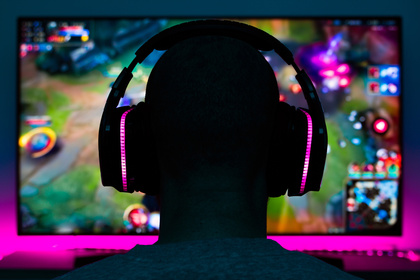 En person med hörlurar sitter framför en datorskärm och spelar ett färgglatt datorspel.