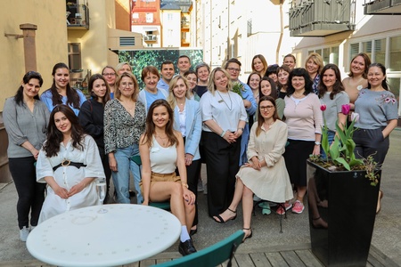 En grupp människor poserar tillsammans utomhus på en innergård, några sitter och andra står.