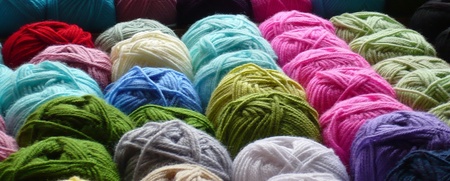 Flera rader med garnnystan i olika färger ligger tätt intill varandra.