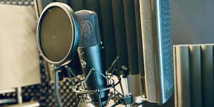 Två mikrofoner med popfilter och ljudisolerande skärmar i en inspelningsstudio.