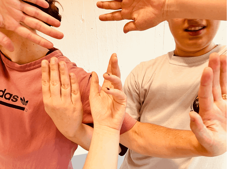 Två personer håller upp händerna framför sig i olika gester mot en ljus bakgrund.