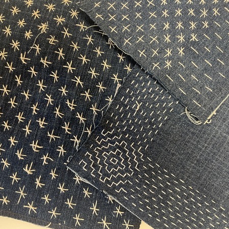 Flera tygbitar i blått med vita broderade mönster i olika geometriska former.