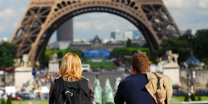 Två personer sitter med ryggen mot kameran och tittar mot Eiffeltornet i Paris.