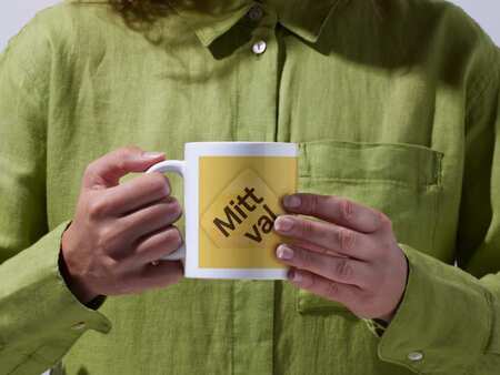 En person i grön skjorta håller i en kopp med en logotyp för Mitt val.