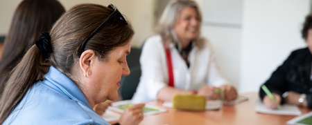 Fyra personer sitter runt ett bord och deltar i ett möte med papper och mobiltelefoner framför sig.