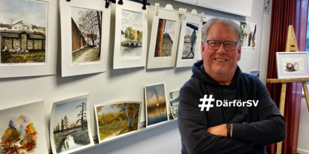 Leende man står framför en vägg med akvarellmålningar i ett konstgalleri.