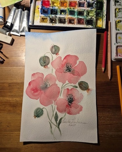 Akvarellmålning av rosa blommor på ett bord med färglåda, penslar och pennor runtom.