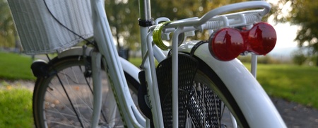 Närbild av bakdelen på en vit cykel med pakethållare och röd baklykta, utomhus på en stig.
