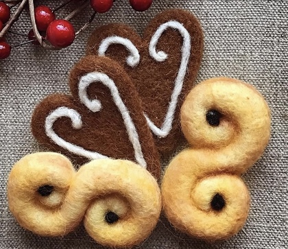 Två gula och två bruna tovade ullfigurer på tyg, dekorerade med vita och svarta detaljer.