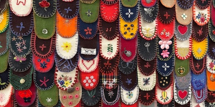 Närbild av färgglada tygbitar med broderade mönster, ordnade som fjäll på en yta.