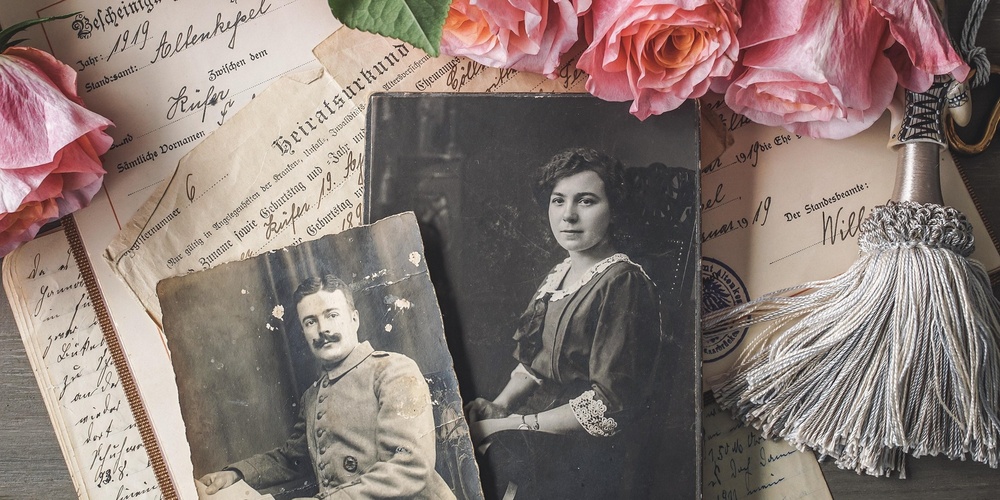 Gamla foton på en bädd av utländska tidningar och rosa rosor.