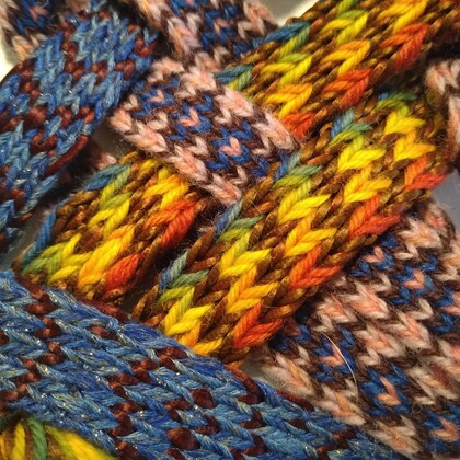 Närbild av färgglada, handvävda band i blått, gult, orange och rosa garn.
