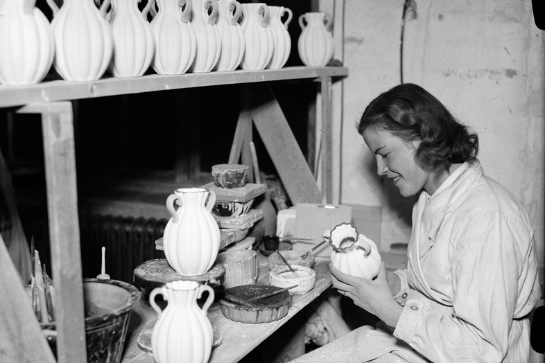 Svartvitt foto på ung kvinna som dekorerar keramikvaser.