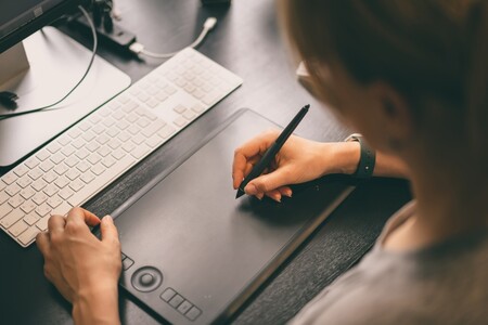 En person arbetar på en dator med en datapenna.