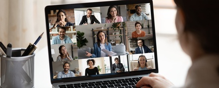 Person deltar i ett videomöte på en bärbar dator med flera deltagare synliga på skärmen.