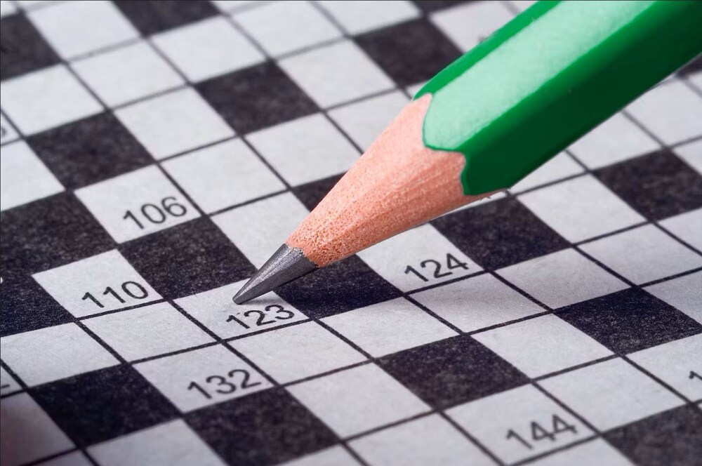 En grön blyertspenna pekar på en ruta i ett korsord med siffror.